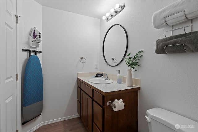 bathroom featuring vanity, wood-type flooring, and toilet