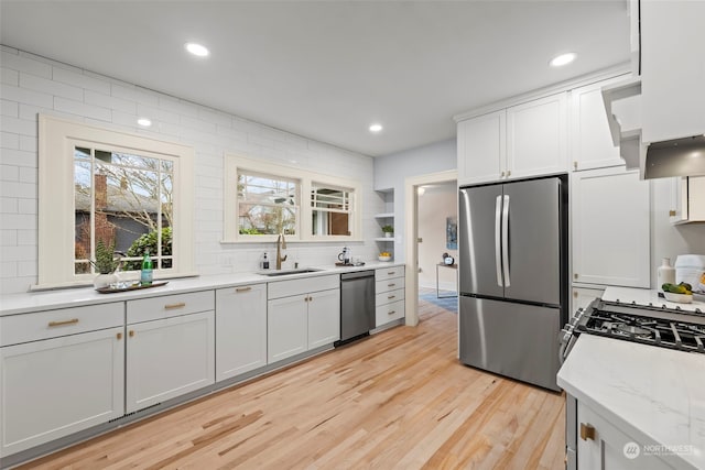 kitchen featuring appliances with stainless steel finishes, sink, white cabinets, and light stone counters