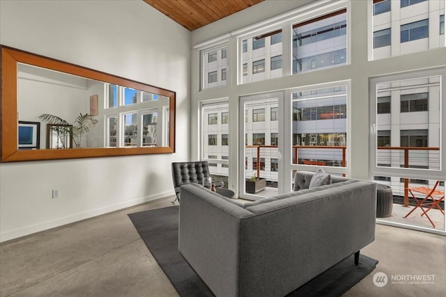 living room with wood ceiling, concrete floors, and a high ceiling