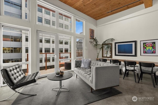 living room with wooden ceiling, concrete floors, and a high ceiling