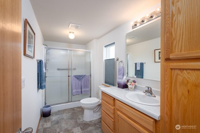 bathroom featuring vanity, toilet, and an enclosed shower