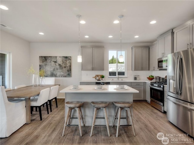 kitchen with pendant lighting, sink, gray cabinets, stainless steel appliances, and a center island