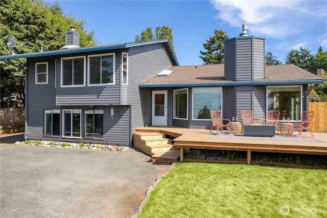 rear view of property with a chimney, fence, a lawn, and a wooden deck