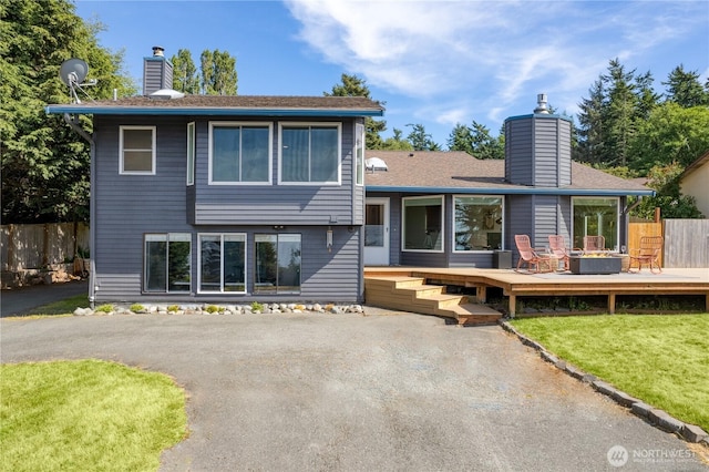 view of front of house with a chimney, fence, and a wooden deck