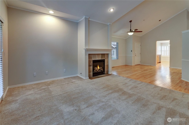 unfurnished living room featuring crown molding, high vaulted ceiling, ceiling fan, light colored carpet, and a fireplace