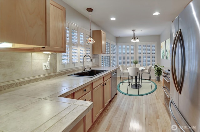 kitchen featuring sink, light brown cabinets, appliances with stainless steel finishes, pendant lighting, and decorative backsplash