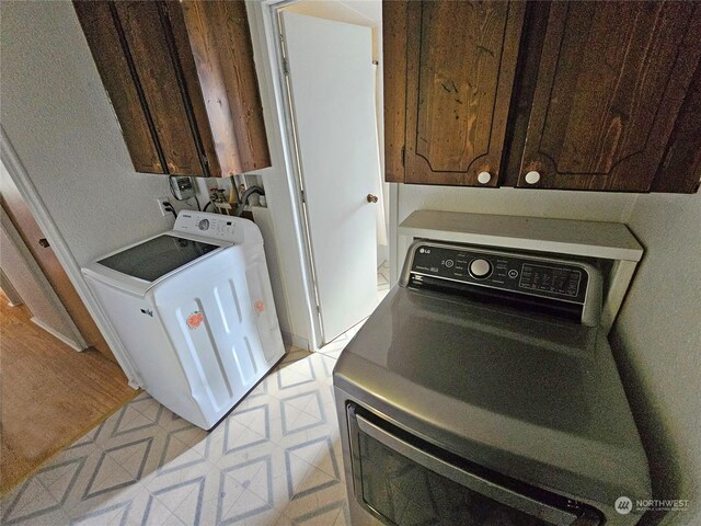 clothes washing area featuring cabinets and separate washer and dryer