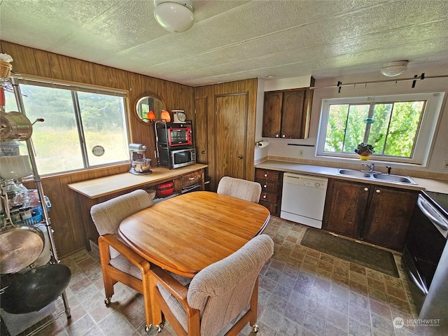 kitchen with sink, electric range, white dishwasher, a textured ceiling, and wood walls