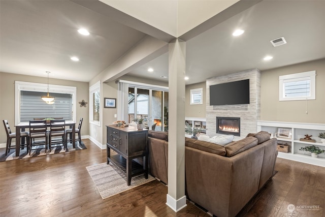 living room featuring dark hardwood / wood-style flooring and a large fireplace