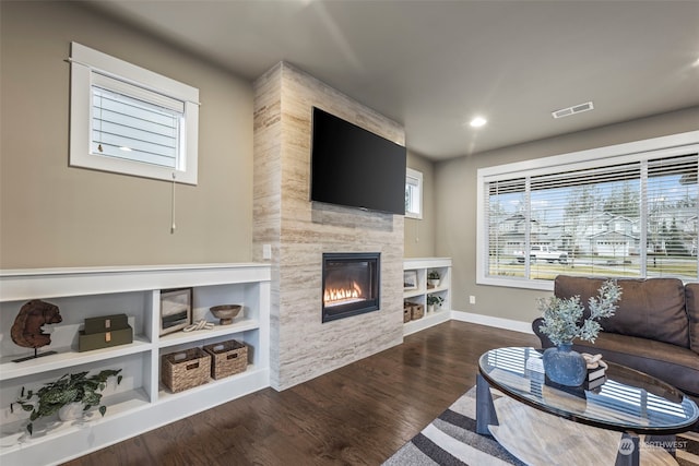 living room featuring dark hardwood / wood-style flooring and a large fireplace