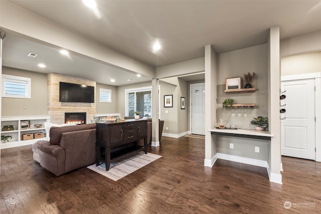 living room with a healthy amount of sunlight, a large fireplace, and dark hardwood / wood-style flooring