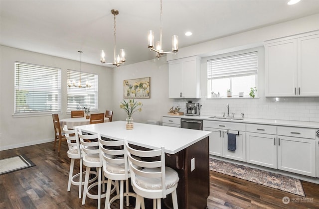 kitchen with sink, decorative light fixtures, white cabinets, and a kitchen island