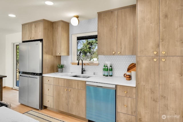 kitchen with stainless steel appliances, tasteful backsplash, a sink, modern cabinets, and light wood-type flooring