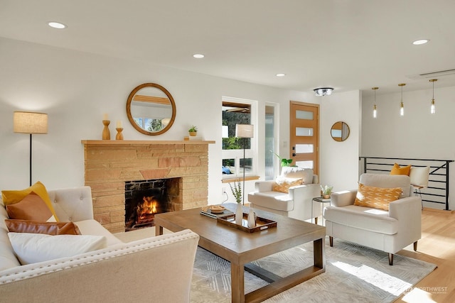 living room with recessed lighting, light wood-style flooring, and a stone fireplace