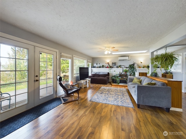 living room with dark wood-type flooring, ceiling fan, a wall mounted air conditioner, a textured ceiling, and french doors