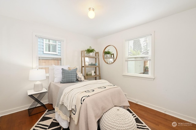 bedroom with multiple windows and dark wood-type flooring