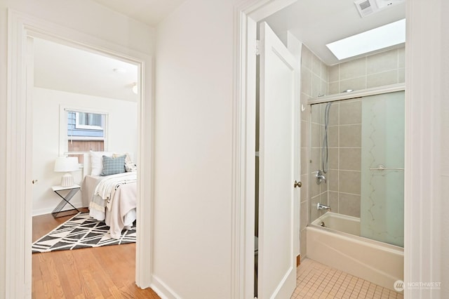 bathroom with tiled shower / bath, a skylight, and hardwood / wood-style floors