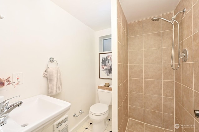 bathroom with tile patterned floors, toilet, sink, and a tile shower