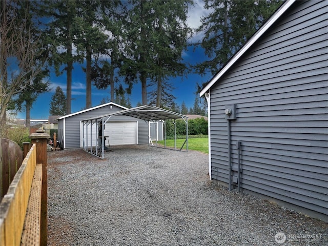 detached garage featuring driveway, fence, and a carport