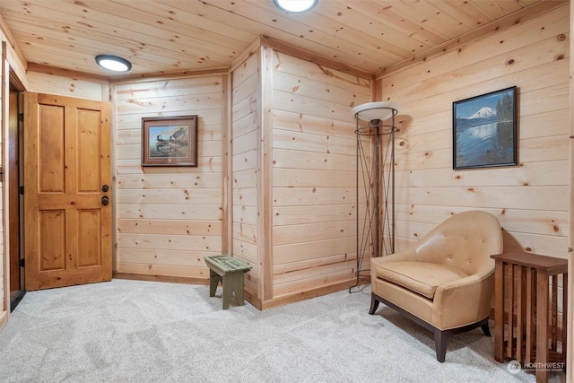 sitting room featuring wood ceiling, wooden walls, and carpet