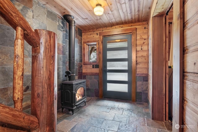 entrance foyer featuring a wood stove, wooden ceiling, and wooden walls