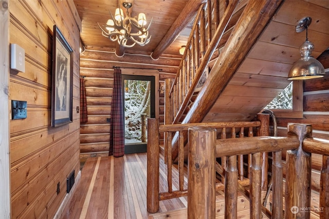 interior space with wood-type flooring, log walls, beam ceiling, wooden ceiling, and an inviting chandelier