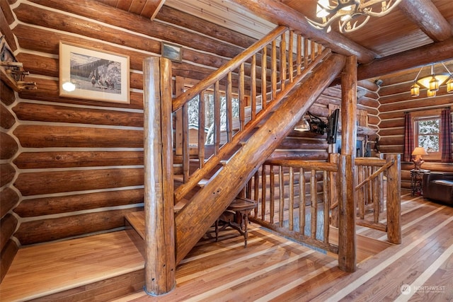 stairway with a chandelier, wood-type flooring, log walls, wooden ceiling, and beamed ceiling