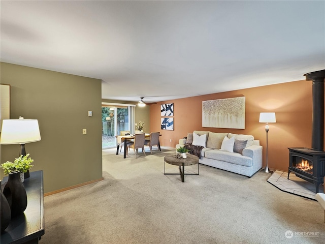 carpeted living room with ceiling fan and a wood stove