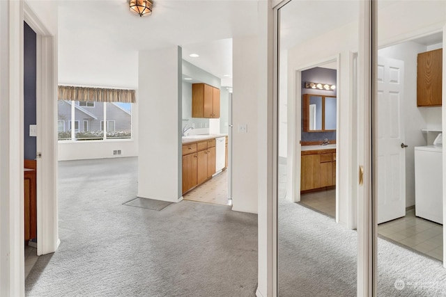 hallway featuring light carpet, sink, and washer / dryer