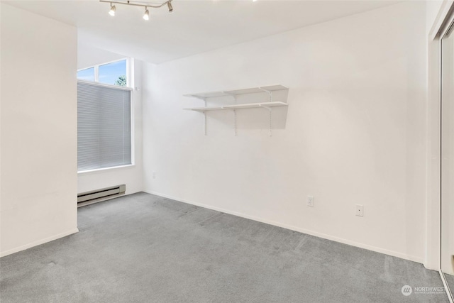 unfurnished room featuring baseboard heating, rail lighting, and light carpet