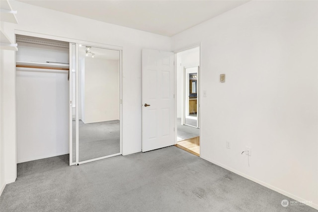 unfurnished bedroom featuring light colored carpet and a closet