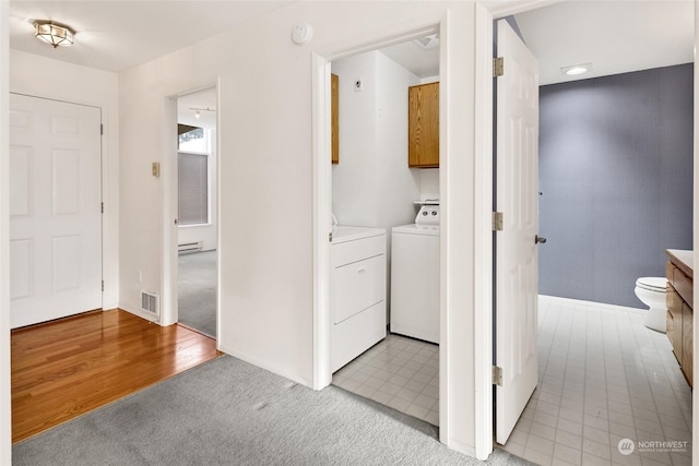 clothes washing area with visible vents, washer and clothes dryer, light carpet, baseboard heating, and cabinet space