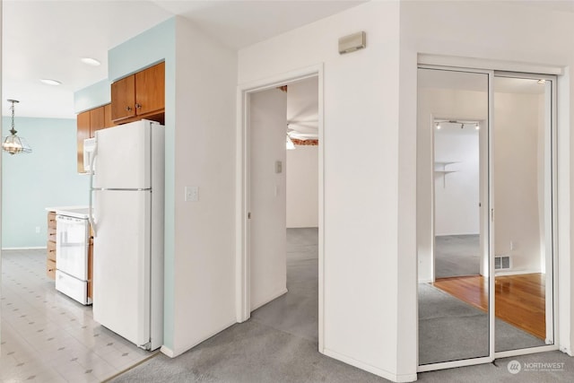 kitchen featuring decorative light fixtures, visible vents, white appliances, and brown cabinets