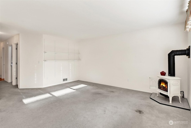 interior space with a wood stove, carpet flooring, and visible vents