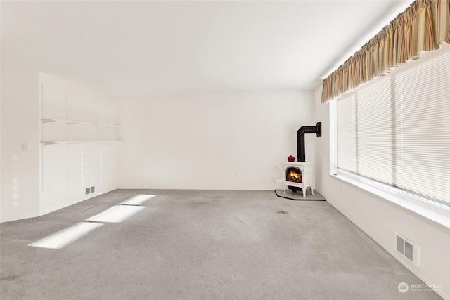 spare room featuring carpet floors and a wood stove