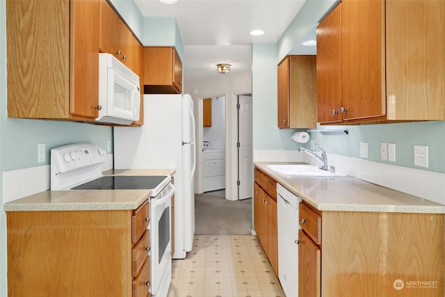 kitchen featuring light floors, brown cabinetry, white appliances, washer / clothes dryer, and a sink