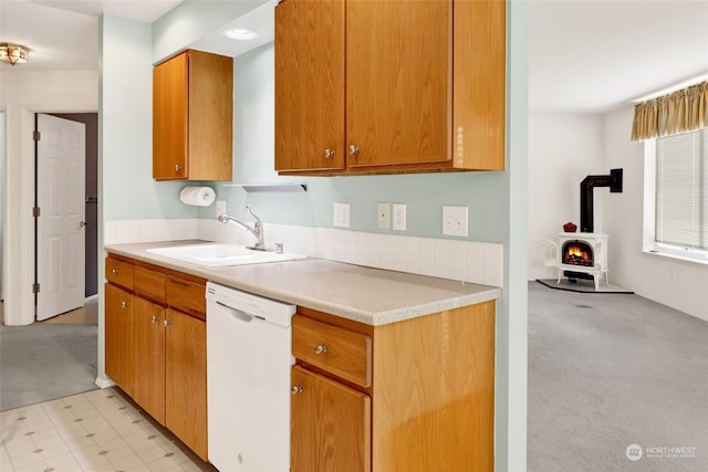 kitchen featuring sink, light colored carpet, dishwasher, and a wood stove