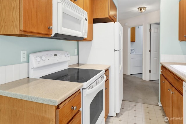 kitchen featuring white appliances, light floors, washer / dryer, and brown cabinetry