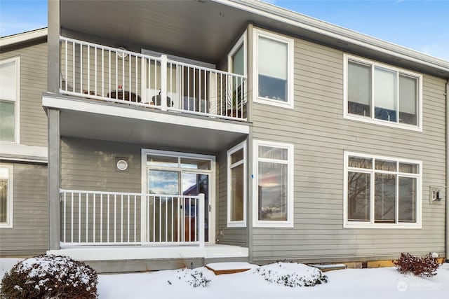 snow covered rear of property with a balcony