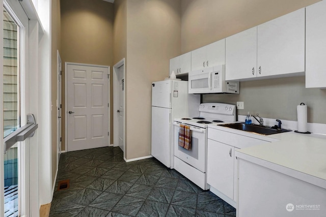 kitchen with visible vents, a sink, white appliances, white cabinets, and light countertops