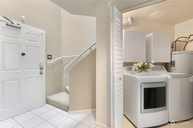 clothes washing area featuring cabinets, light tile patterned flooring, and washing machine and clothes dryer