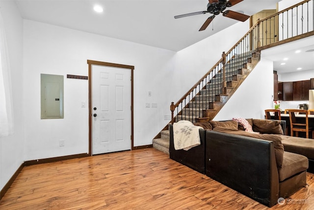 living room featuring electric panel, ceiling fan, and light wood-type flooring