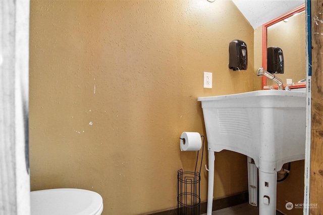 bathroom featuring lofted ceiling and toilet