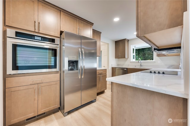 kitchen with light stone counters, light hardwood / wood-style flooring, and stainless steel appliances