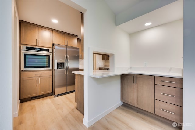 kitchen with stainless steel appliances, light hardwood / wood-style floors, and kitchen peninsula