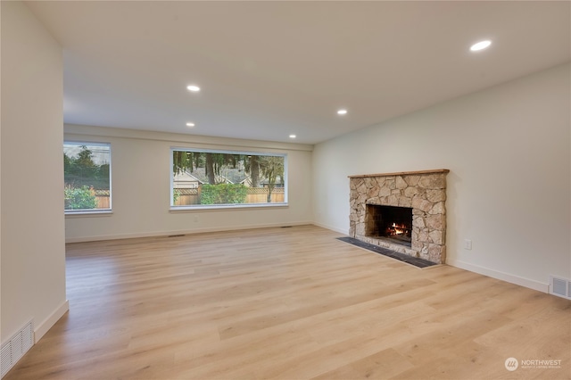 unfurnished living room featuring a stone fireplace and light hardwood / wood-style flooring