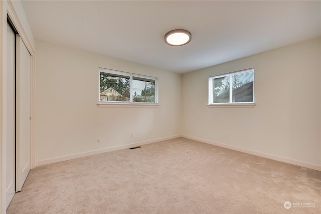 unfurnished bedroom featuring a closet and light carpet