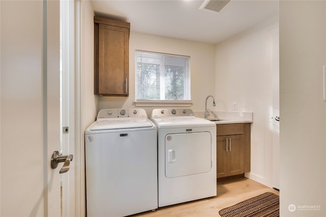 laundry area with separate washer and dryer, sink, light hardwood / wood-style floors, and cabinets