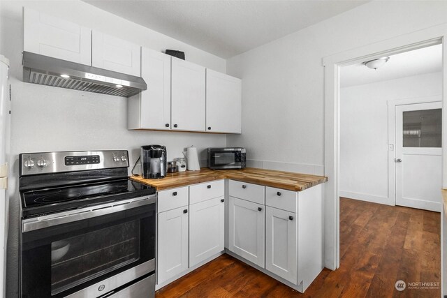 kitchen featuring white cabinets, appliances with stainless steel finishes, butcher block counters, and wall chimney range hood