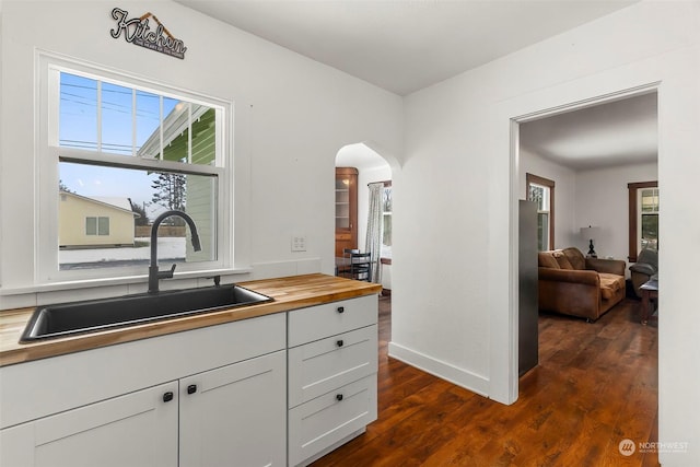 kitchen with wooden counters, sink, dark wood-type flooring, and white cabinets